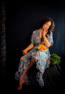 portrait of a woman in blue floral dress holding oranges on dark background Alexandra King Blue Belle Dress