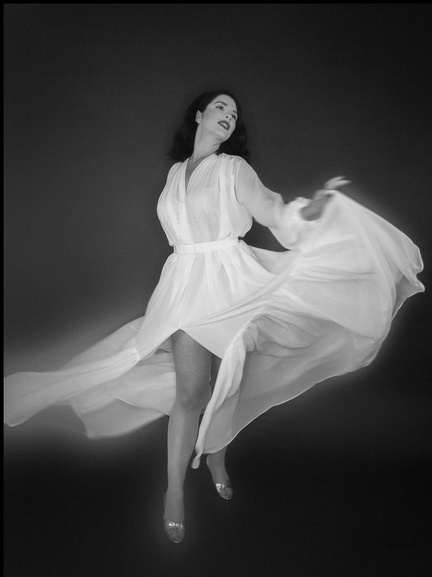 Woman in a flowing white dress against a dark background