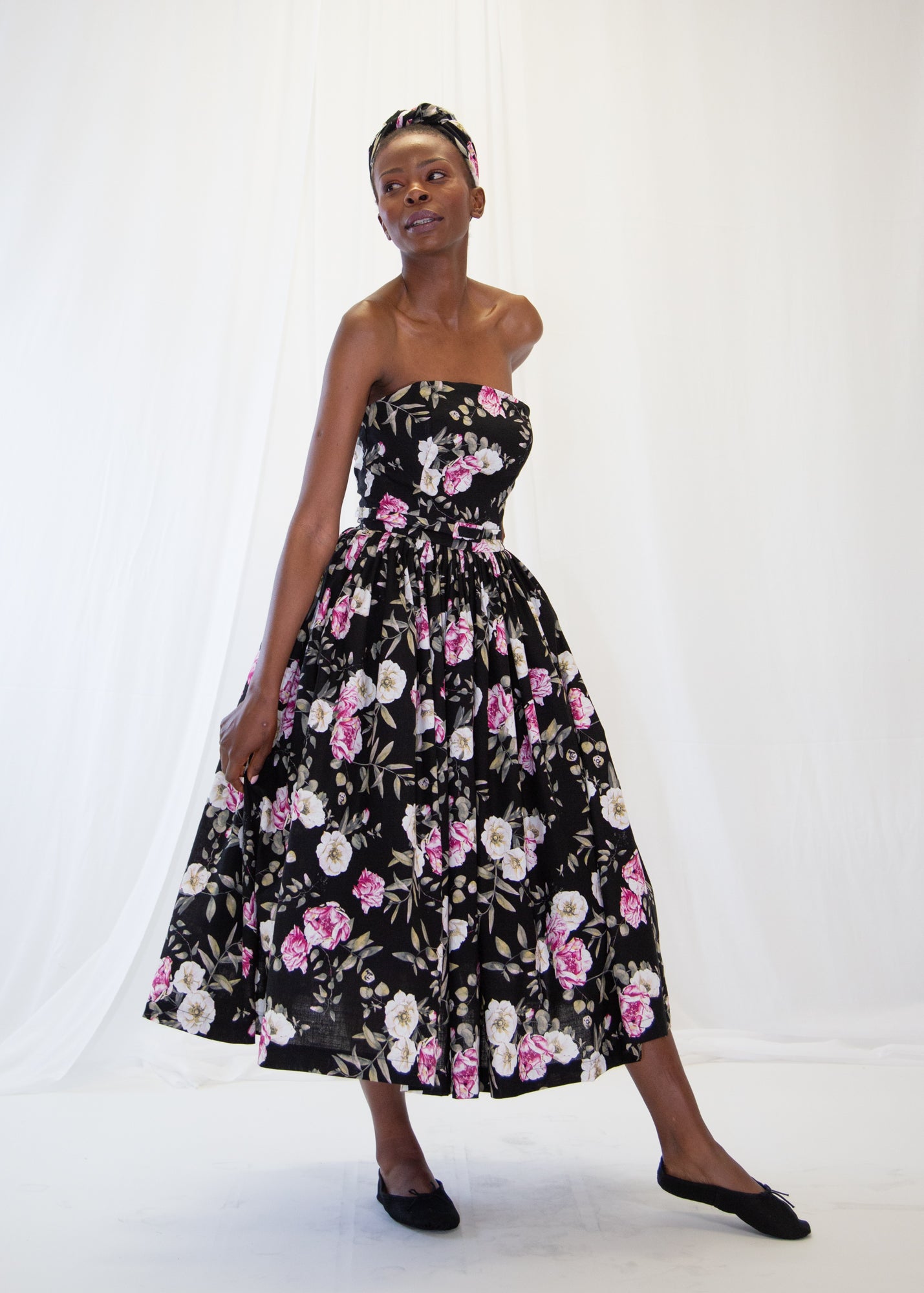 Woman wearing a black floral strapless dress on a white background
