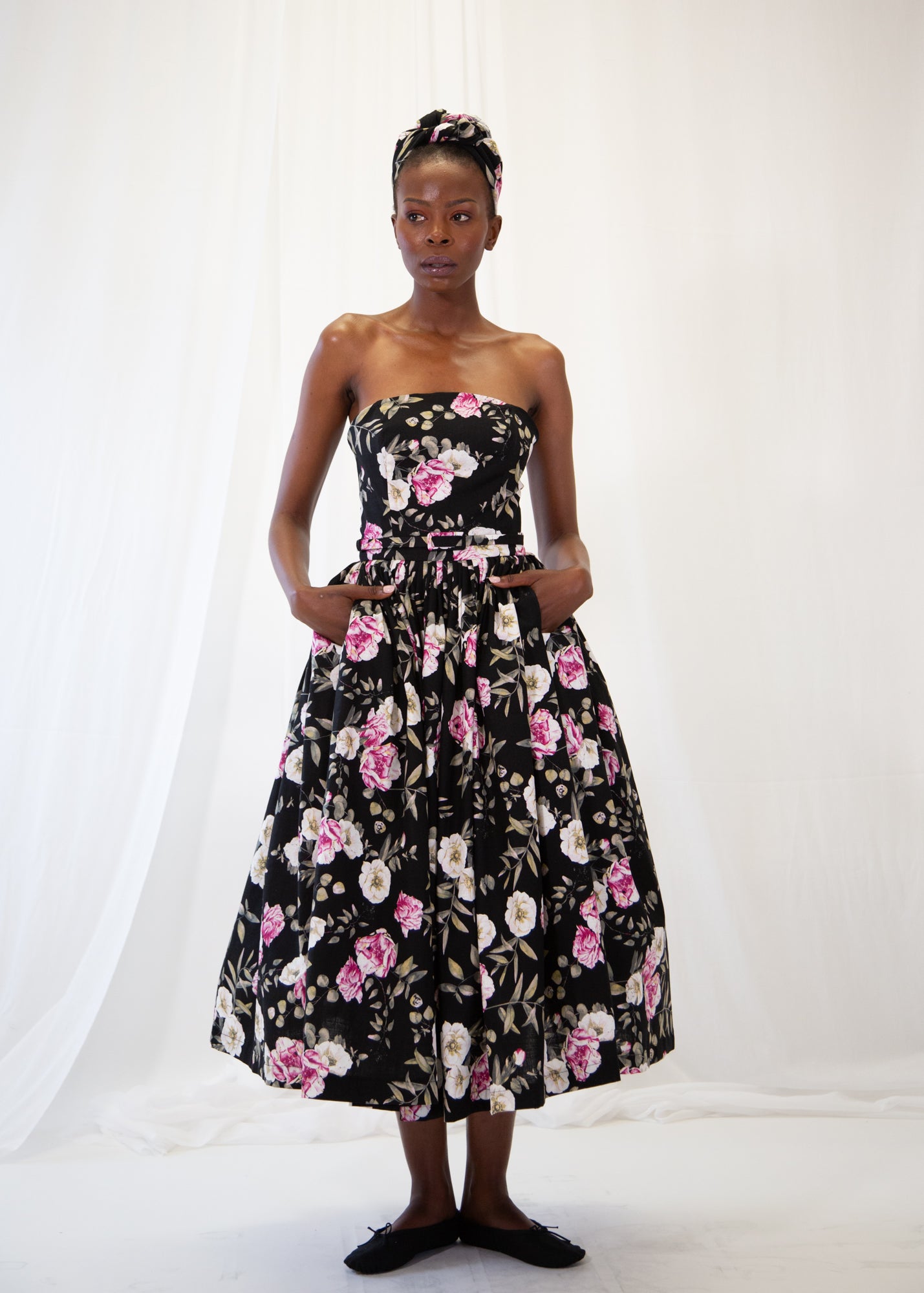 Woman wearing a strapless floral dress against a white background