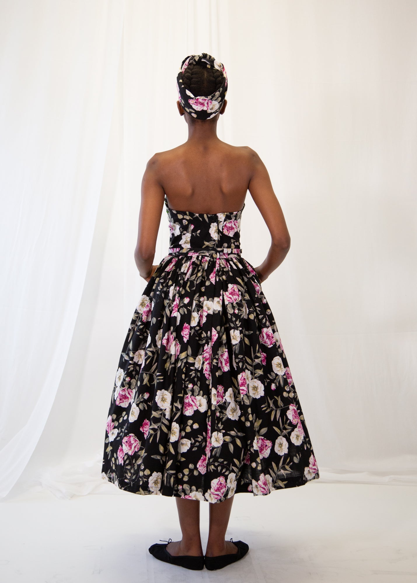 Woman wearing a black floral dress with a white background