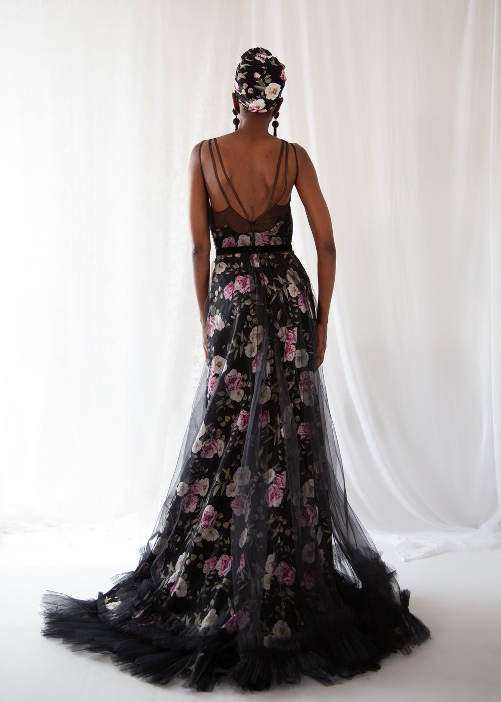 Woman wearing a black floral evening gown with a white background