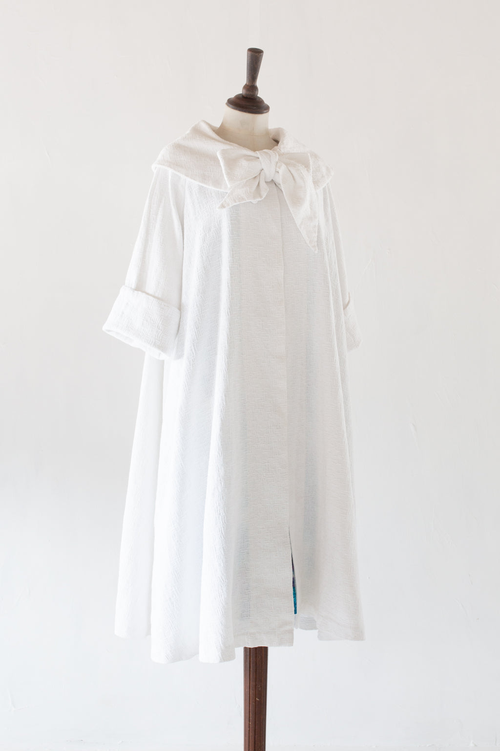 vintage 1950s white cotton swing coat on a mannequin against a white background