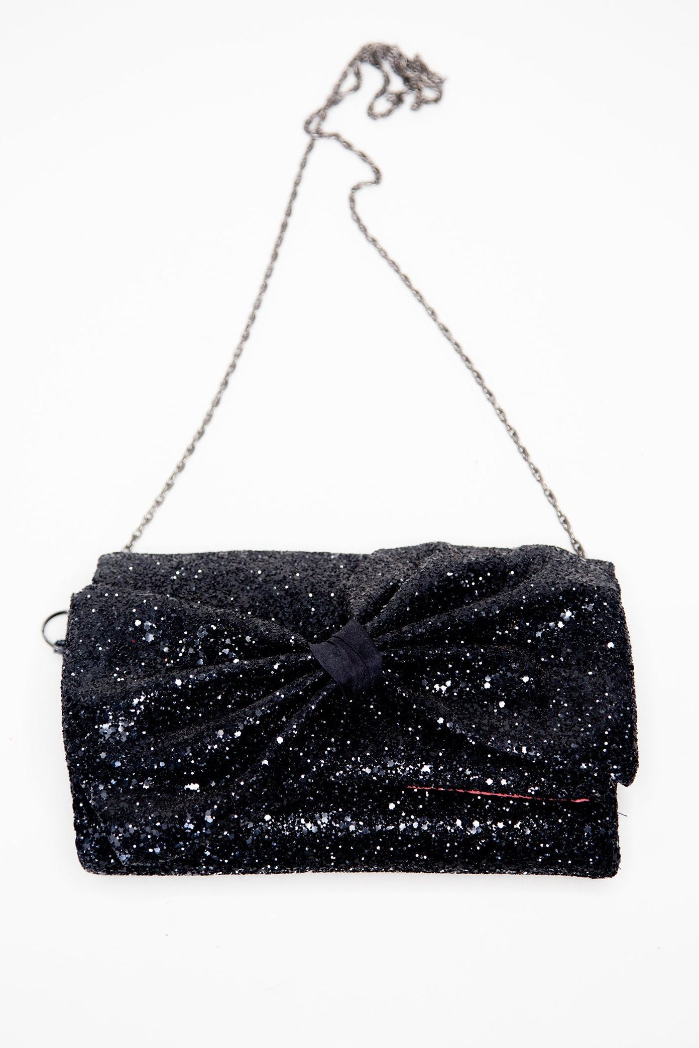 A black glittery clutch bag with a large asymmetric bow over the flap and a chain strap.