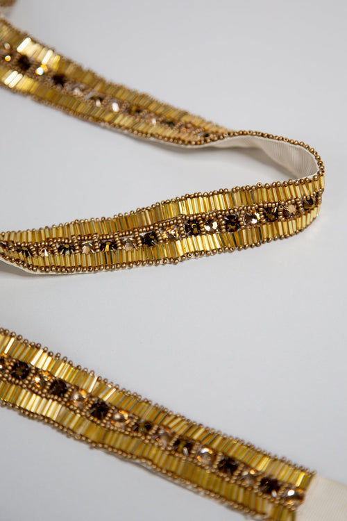 A metallic gold 1920s style art deco design belt with hand beaded Swarovski rhinestones and glass beads on a vintage tone grosgrain ribbon.