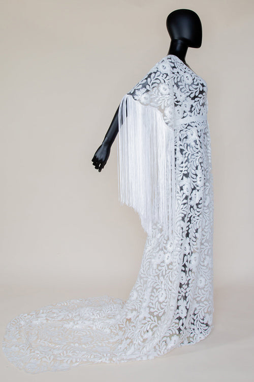 A white bridal robe with sequin embellishments and tassel detailing, displayed on a mannequin against a neutral background.