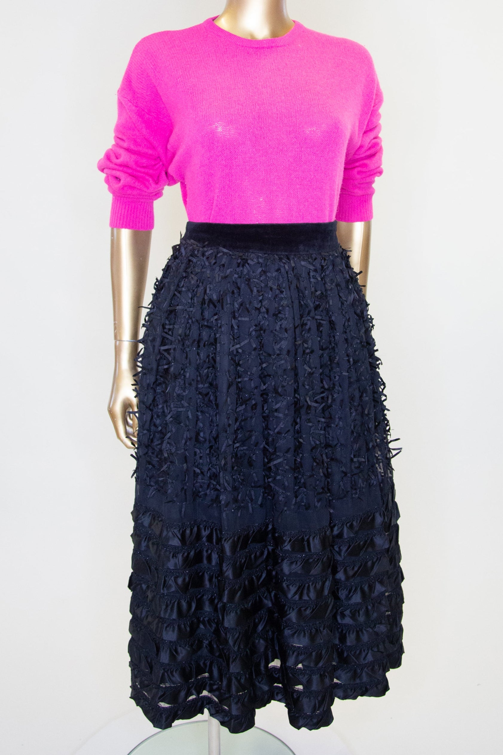 Vintage 1980s black satin ribbon work midi skirt on a mannequin, featuring a fitted waist and a flared skirt with ribbon embellishments and a stripe hem.