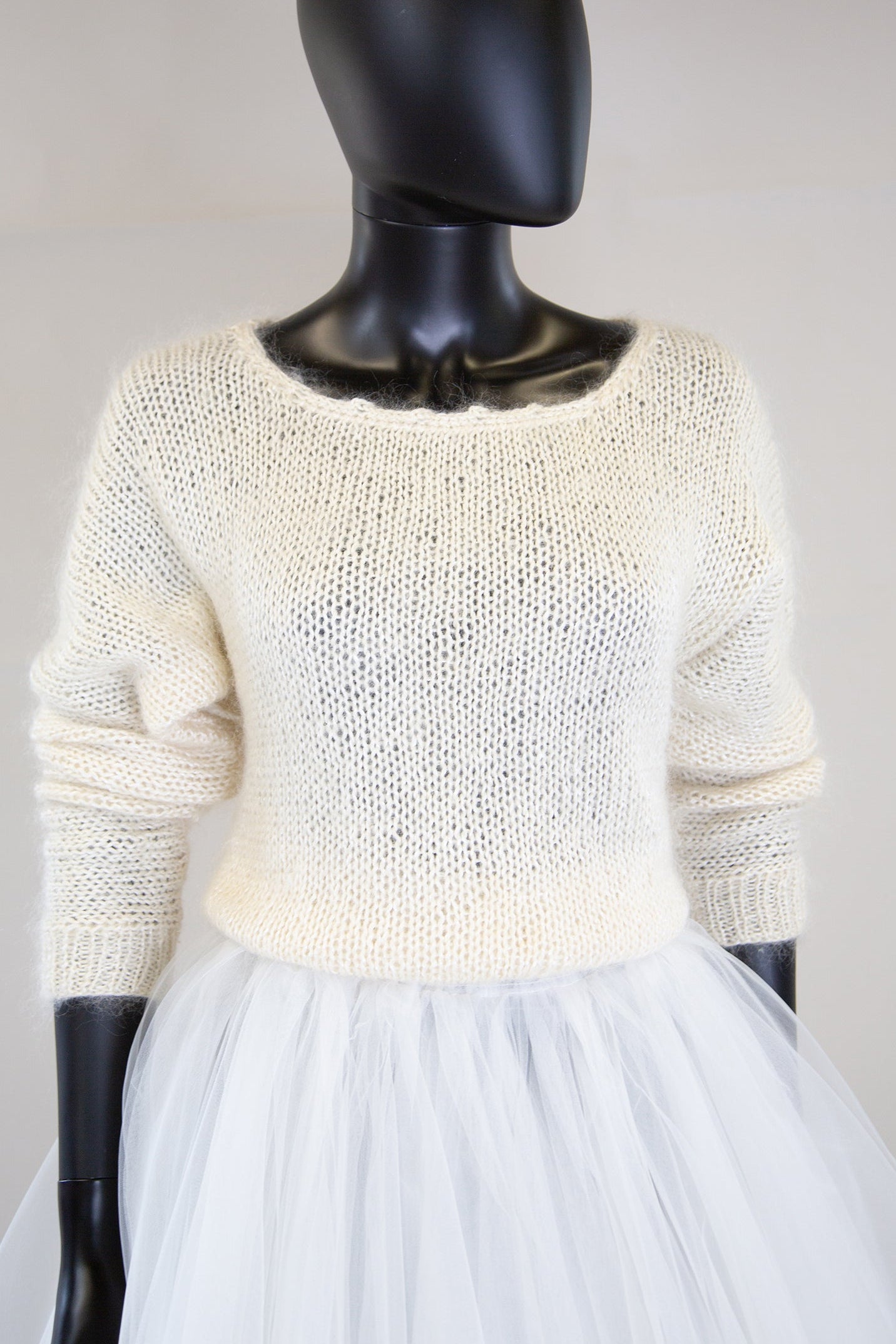 A vintage 1980s ivory hand knitted angora mix sweater displayed on a mannequin with long sleeves and a wide neckline.